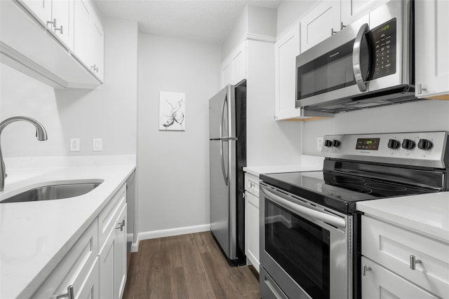 kitchen featuring stainless steel appliances, white cabinetry, sink, and dark hardwood / wood-style floors