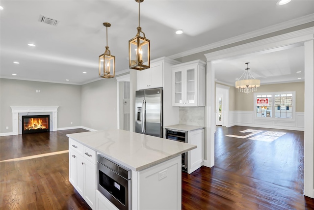 kitchen with a kitchen island, white cabinetry, beverage cooler, hanging light fixtures, and stainless steel appliances