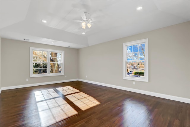 empty room featuring dark hardwood / wood-style flooring, ceiling fan, vaulted ceiling, and a healthy amount of sunlight