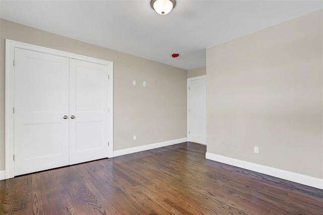 unfurnished bedroom featuring dark wood-type flooring and a closet