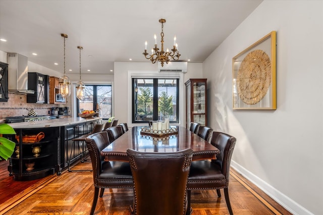 dining space with an inviting chandelier, parquet flooring, a wall mounted air conditioner, and french doors