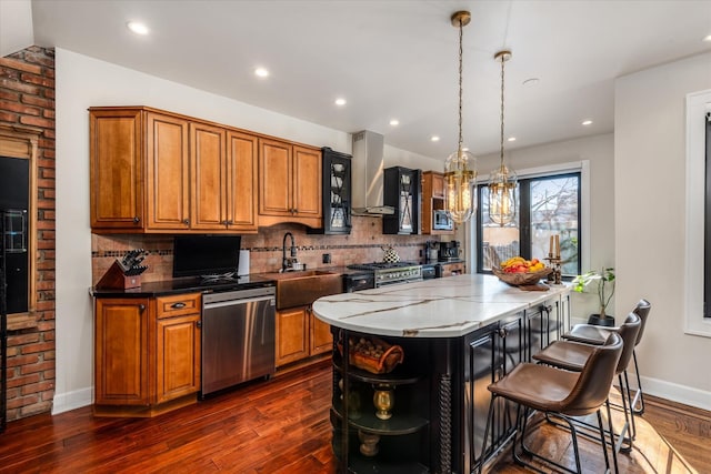 kitchen with sink, appliances with stainless steel finishes, dark stone countertops, hanging light fixtures, and a kitchen island