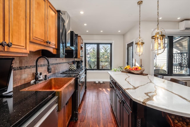 kitchen with appliances with stainless steel finishes, backsplash, light stone counters, dark wood-type flooring, and a wall unit AC