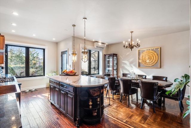 kitchen with an inviting chandelier, a wall unit AC, a healthy amount of sunlight, and a kitchen island