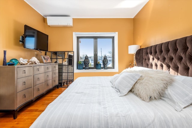 bedroom featuring a wall mounted air conditioner and light hardwood / wood-style floors