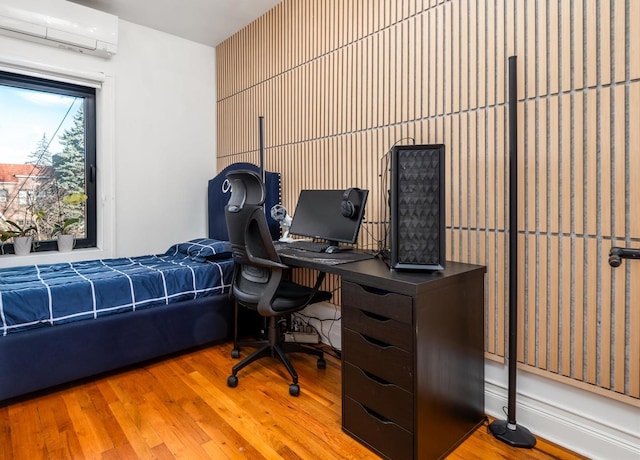 bedroom with a wall unit AC and light hardwood / wood-style floors