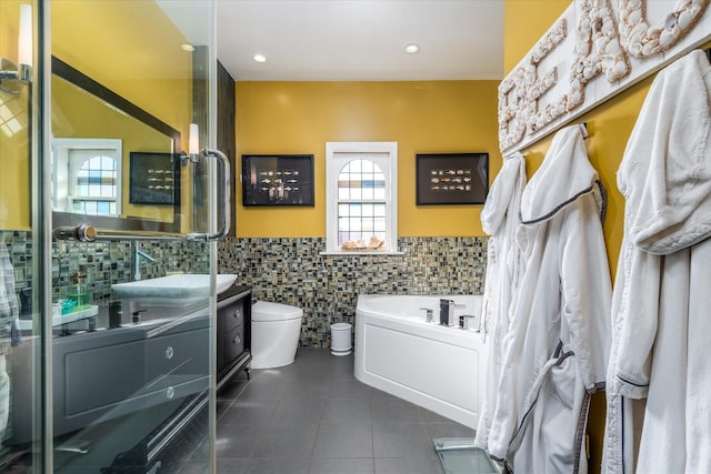 bathroom featuring tile walls, vanity, tile patterned floors, toilet, and a bathing tub