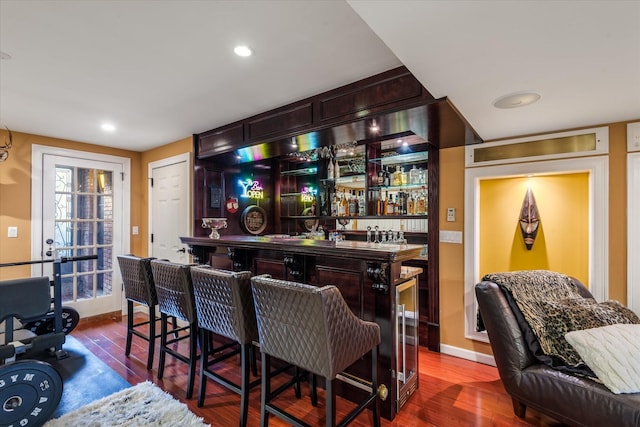 bar with hardwood / wood-style floors and dark brown cabinets