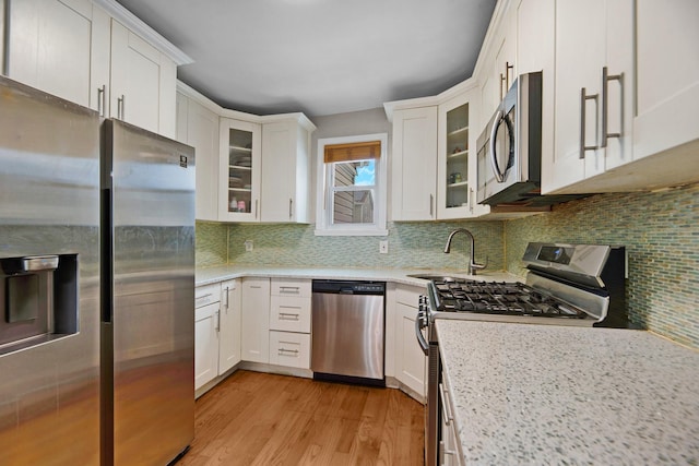 kitchen featuring stainless steel appliances, white cabinetry, sink, and light hardwood / wood-style flooring