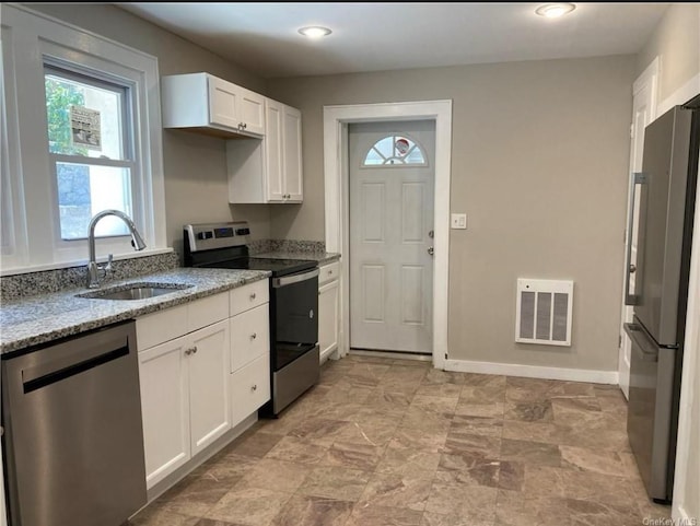 kitchen with sink, stainless steel appliances, white cabinets, and light stone countertops