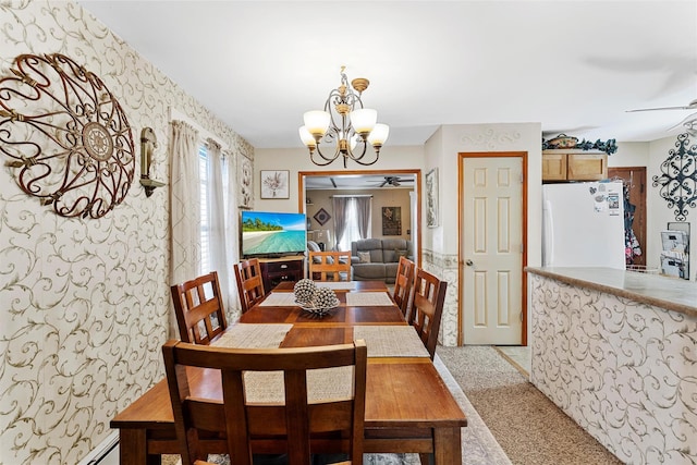 carpeted dining space featuring a baseboard heating unit and ceiling fan with notable chandelier