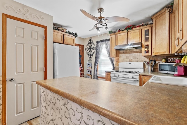 kitchen with kitchen peninsula, sink, white appliances, ceiling fan, and decorative backsplash