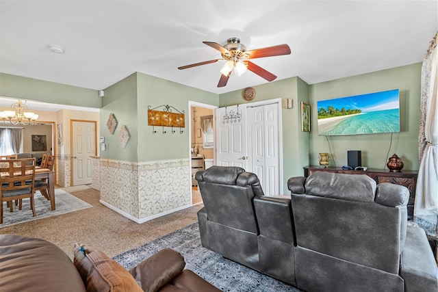 living room with ceiling fan with notable chandelier and carpet