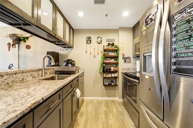 kitchen with light stone counters, light wood-style flooring, a sink, visible vents, and appliances with stainless steel finishes