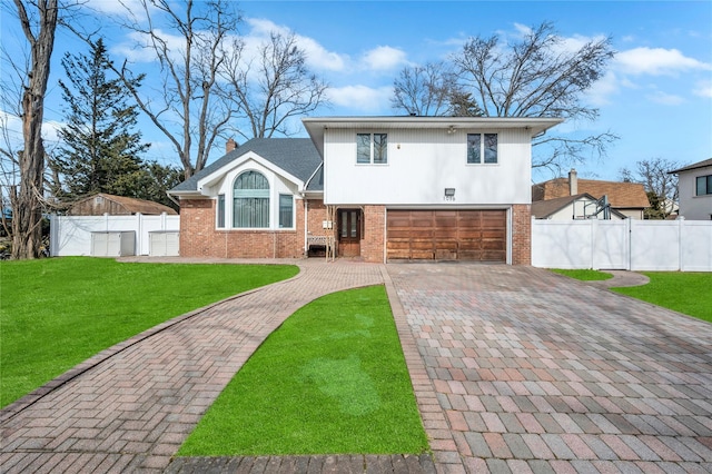 split level home with a front yard, fence, decorative driveway, and brick siding