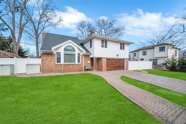 tri-level home with brick siding, fence, decorative driveway, a chimney, and a front yard