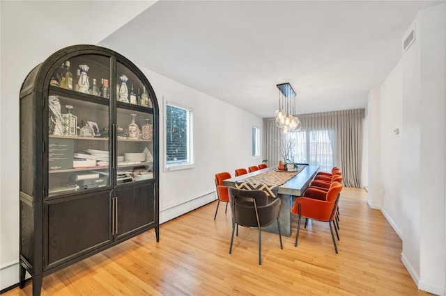 dining space with light wood-style flooring, a notable chandelier, a baseboard heating unit, visible vents, and baseboards