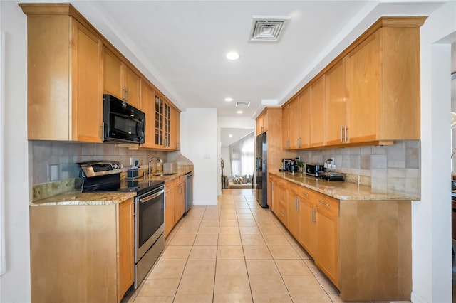 kitchen with glass insert cabinets, visible vents, black appliances, and light stone countertops