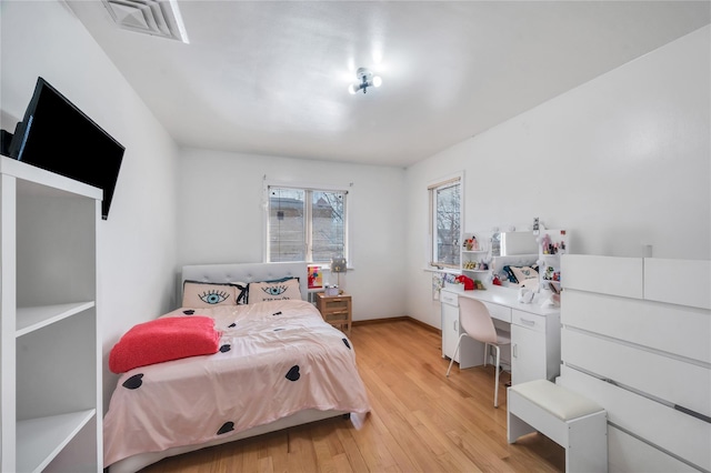 bedroom with baseboards, visible vents, and light wood-style floors