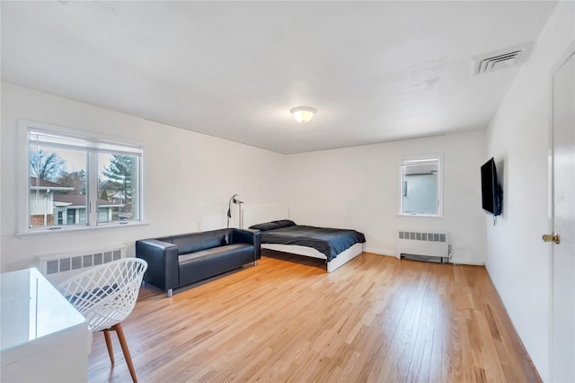 bedroom featuring wood finished floors, visible vents, and radiator