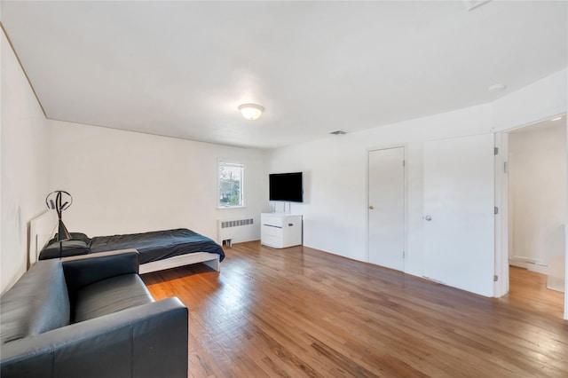 bedroom with radiator, visible vents, and wood finished floors