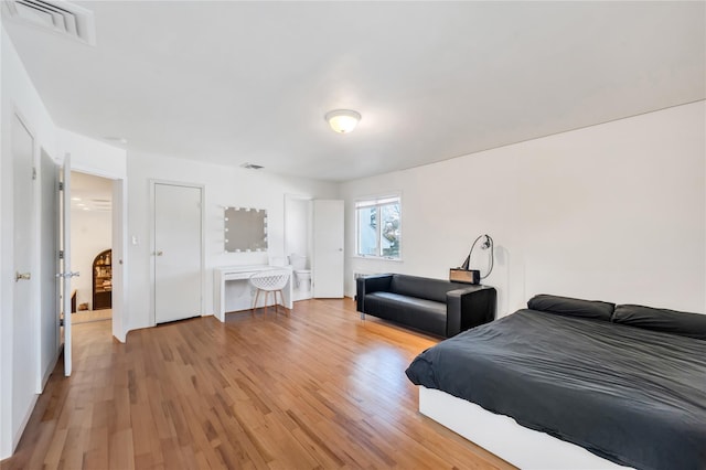 bedroom with light wood-style floors and visible vents