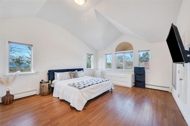 bedroom featuring vaulted ceiling, baseboard heating, wood finished floors, and freestanding refrigerator