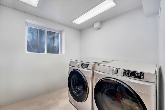 clothes washing area featuring laundry area, light tile patterned floors, and washer and clothes dryer