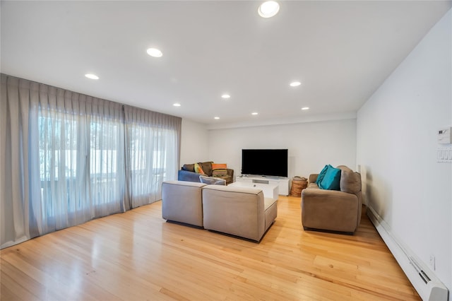 living room featuring baseboard heating, light wood-type flooring, and recessed lighting