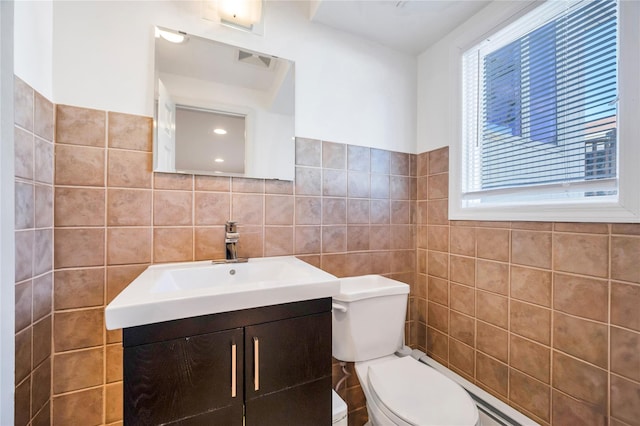 bathroom with toilet, vanity, and tile walls