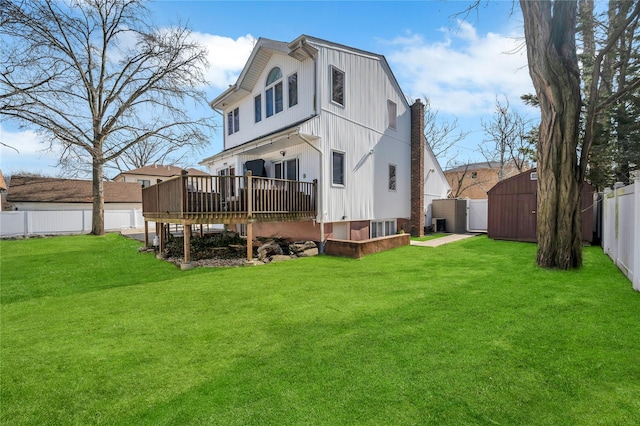 rear view of house with a fenced backyard, an outdoor structure, a wooden deck, and a storage unit