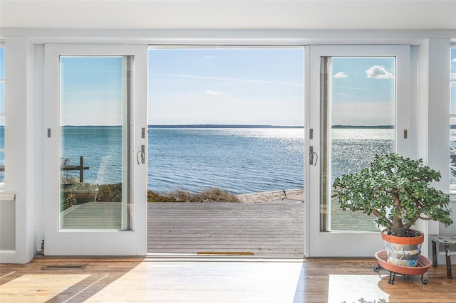 doorway to outside featuring visible vents, a water view, a healthy amount of sunlight, and wood finished floors