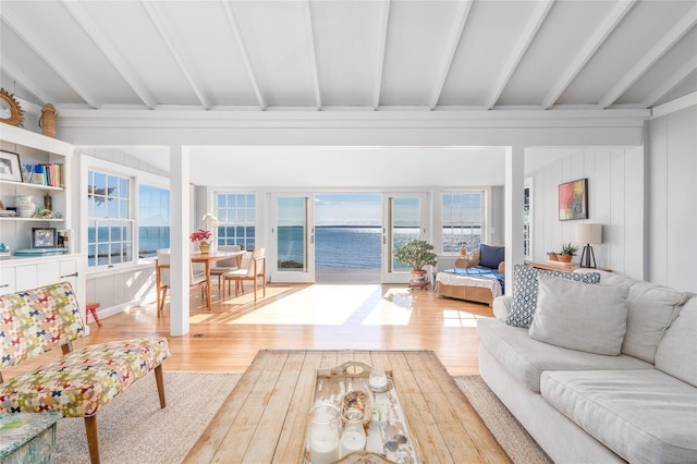 living room featuring a water view, wood finished floors, and vaulted ceiling with beams