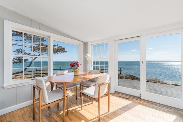 sunroom featuring vaulted ceiling, visible vents, and a water view