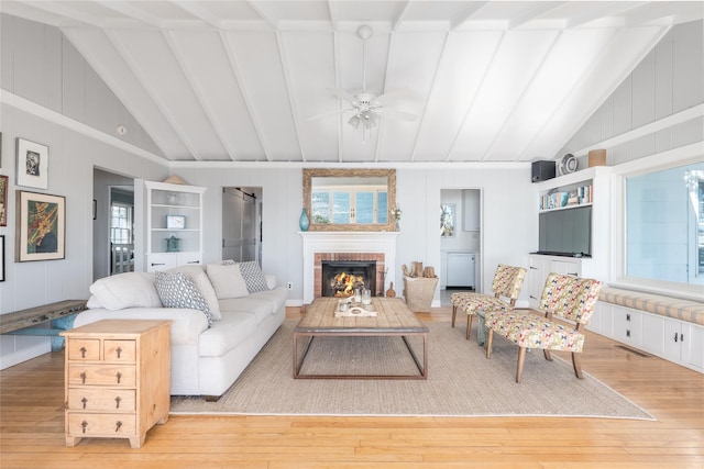 living area featuring a wealth of natural light, a brick fireplace, and vaulted ceiling with beams