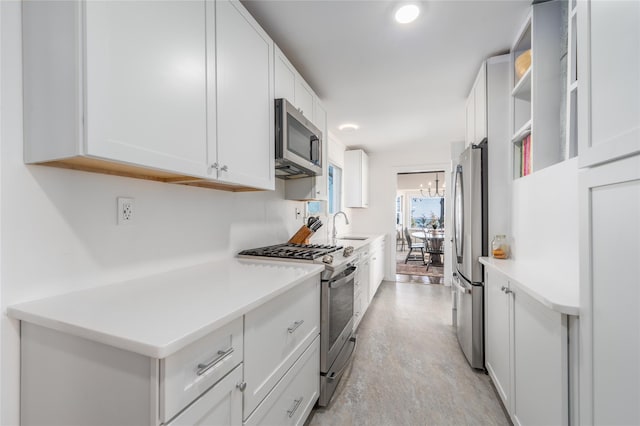 kitchen with a chandelier, light countertops, appliances with stainless steel finishes, white cabinetry, and a sink