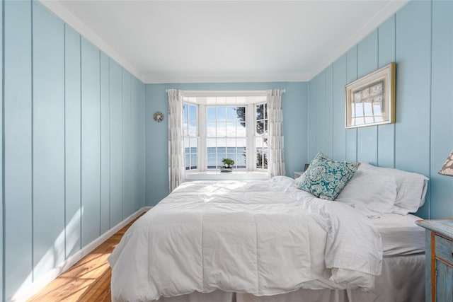 bedroom featuring multiple windows, crown molding, and wood finished floors