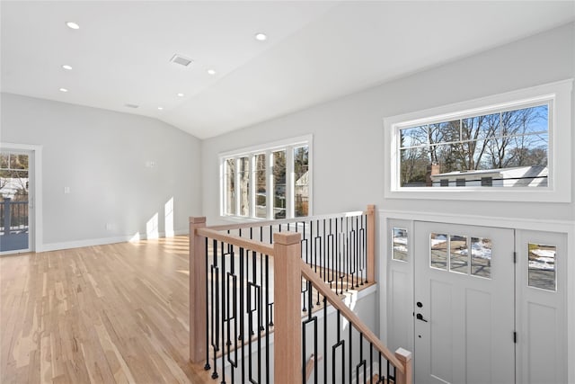 hall with lofted ceiling and light hardwood / wood-style floors