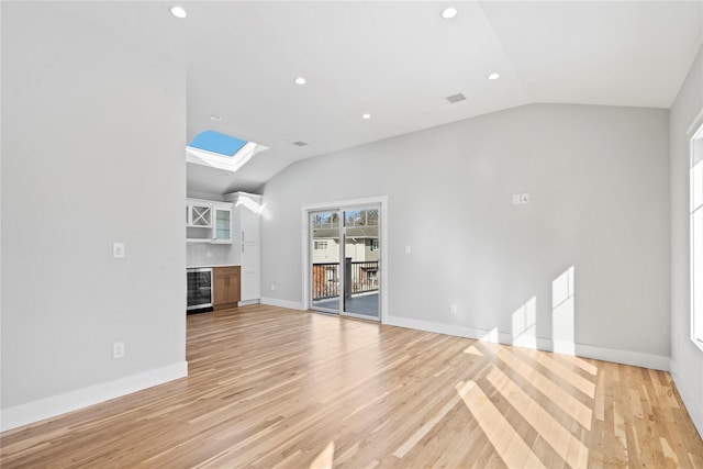 unfurnished living room featuring lofted ceiling, bar area, wine cooler, and light hardwood / wood-style floors