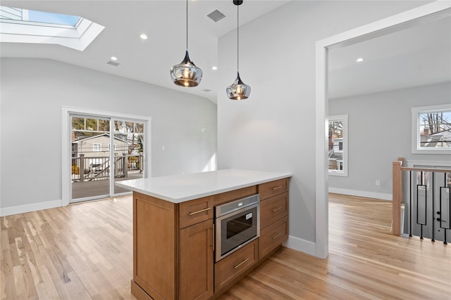 kitchen with lofted ceiling with skylight, pendant lighting, and light hardwood / wood-style floors