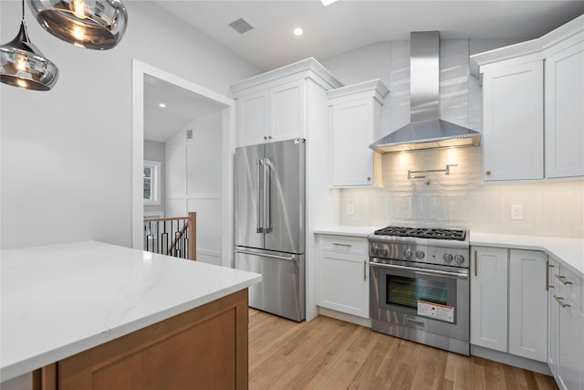 kitchen with white cabinets, wall chimney exhaust hood, decorative backsplash, and premium appliances