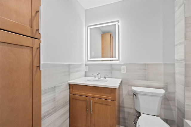 bathroom with tile walls, vanity, and toilet