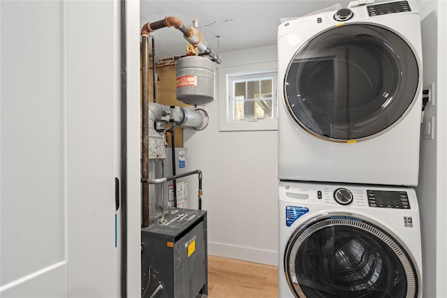 laundry room with stacked washer / drying machine and light hardwood / wood-style flooring