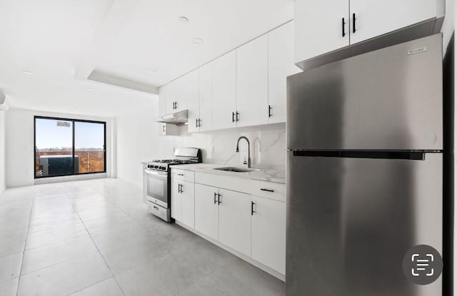 kitchen with sink, white cabinetry, backsplash, stainless steel appliances, and light stone counters