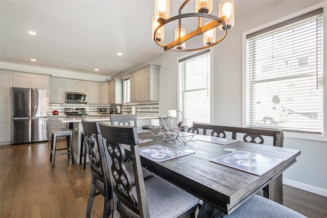 dining space featuring a chandelier, baseboards, dark wood finished floors, and recessed lighting