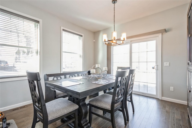 dining space with dark wood-style floors, visible vents, baseboards, and an inviting chandelier