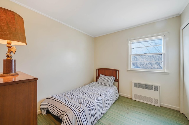 bedroom featuring radiator, hardwood / wood-style flooring, and crown molding