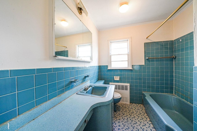 full bathroom featuring tile walls, vanity, tiled shower / bath, radiator heating unit, and toilet