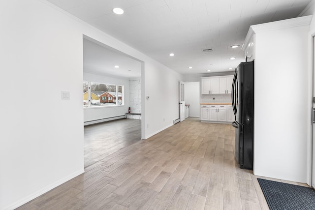 kitchen featuring a baseboard radiator, light wood-style flooring, white cabinets, freestanding refrigerator, and tasteful backsplash