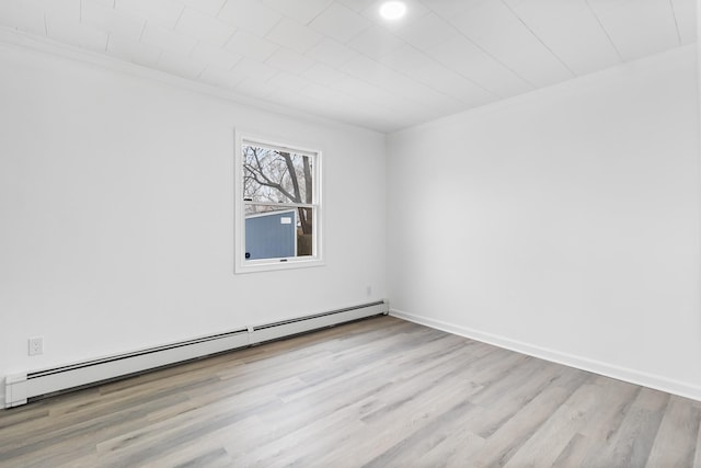 spare room with light wood-type flooring, a baseboard radiator, crown molding, and baseboards